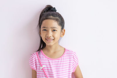 Portrait of a smiling girl standing against white background