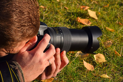 Cropped image of woman holding camera on field