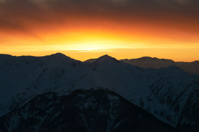 Scenic view of snowcapped mountains against sky during sunset