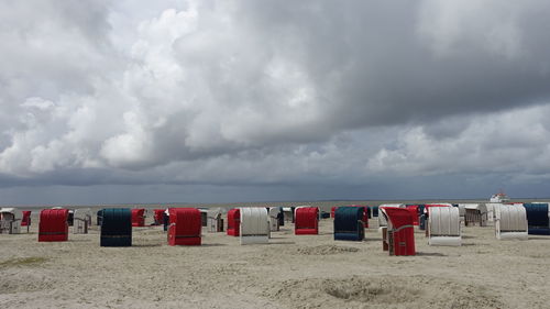Row of hooded chairs at beach against sky