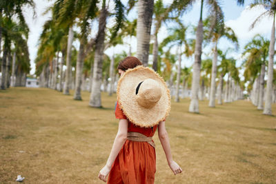 Rear view of woman standing by trees on field