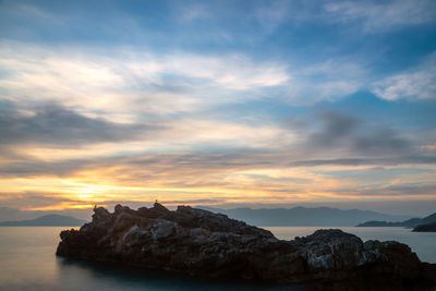 Rock formations by sea against sky during sunset