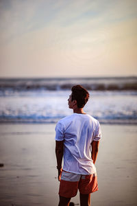 Man standing on beach against sky during sunset