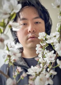 Close-up of young asian man framed by cherry plum blossoms.