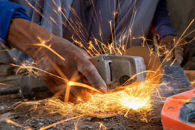 Midsection of male worker cutting metal with circular saw in workshop