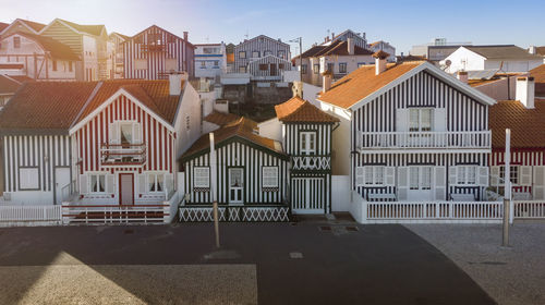 Striped colorful houses in city against clear sky and sun flair