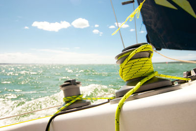 Close-up of cropped boat cleats tied with green rope on sea