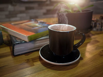 Hot coffee or tea, cocoa, chocolate cup and books on the wooden table in coffee shop.