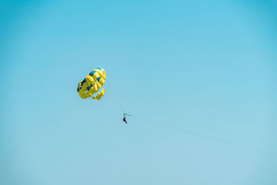 Low angle view of person paragliding against clear blue sky