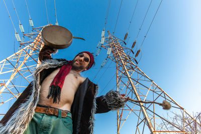 Low angle view of man standing against blue sky