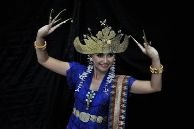 Portrait of smiling young woman in traditional clothing against black background