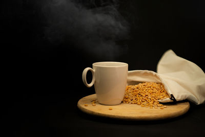 Close-up of coffee cup on table against black background