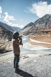 Full length of man photographing on mountain against sky