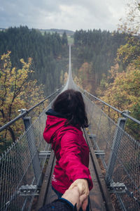 Woman standing on footbridge in forest