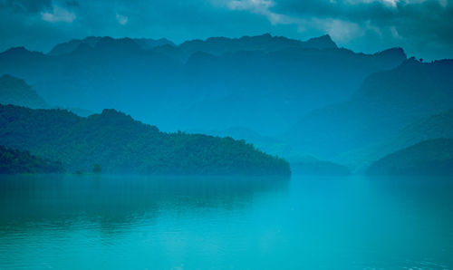 Scenic view of lake and mountains against blue sky