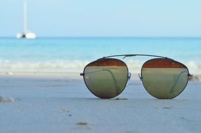 Close-up of sunglasses against sky on beach