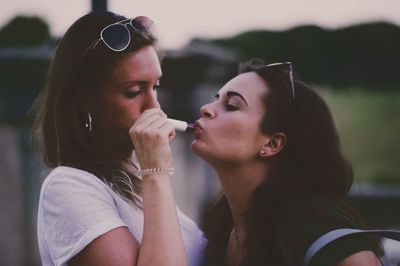 Close-up of woman applying lipstick to friend outdoors