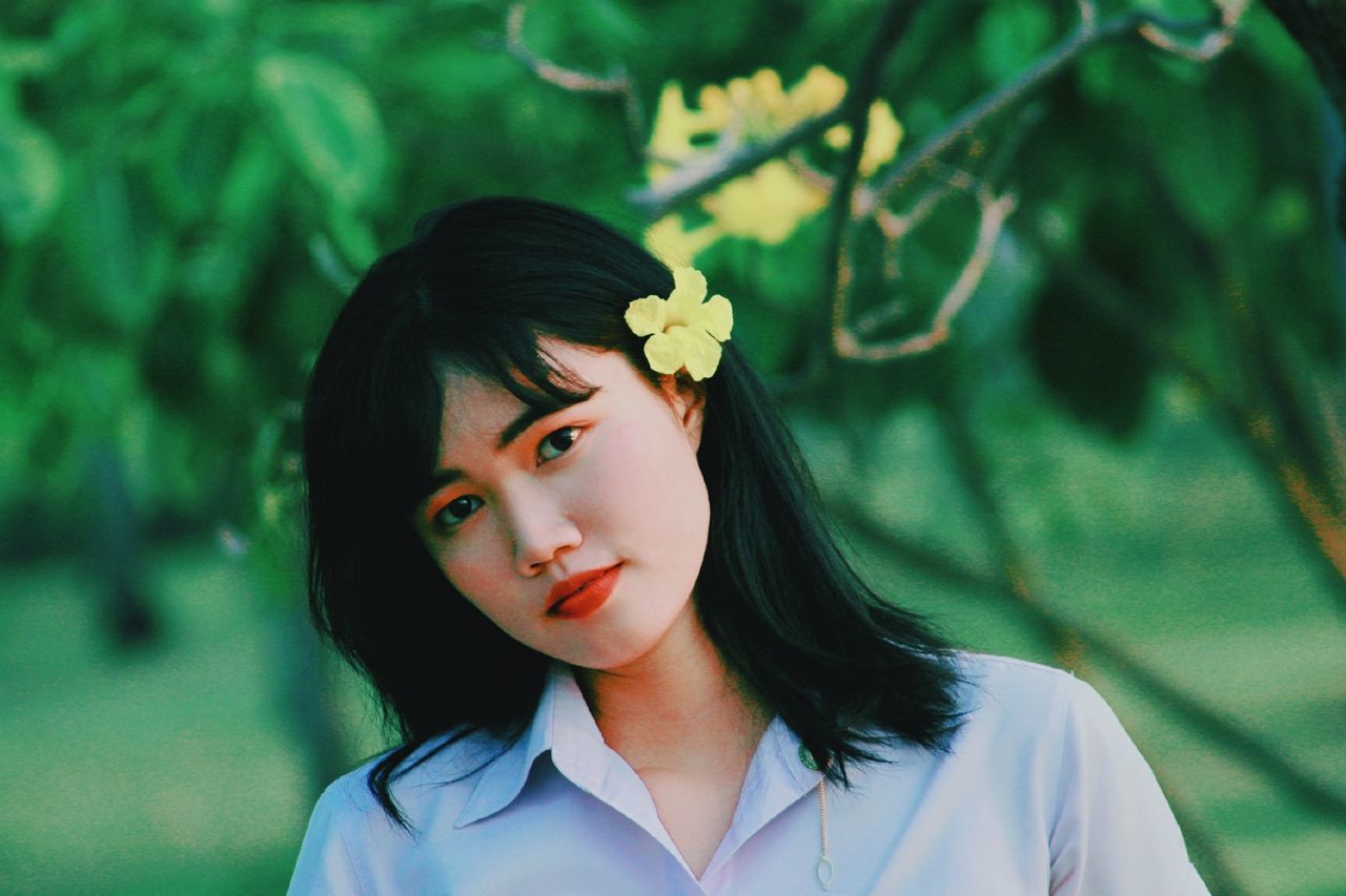 portrait, headshot, one person, plant, real people, looking at camera, focus on foreground, front view, flower, young women, leisure activity, lifestyles, young adult, flowering plant, day, hairstyle, hair, close-up, beautiful woman, outdoors, contemplation