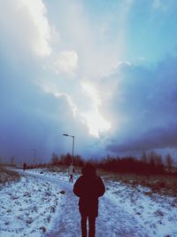 Rear view of silhouette man standing on snow covered field