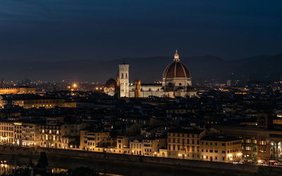 Illuminated buildings in city against sky at night