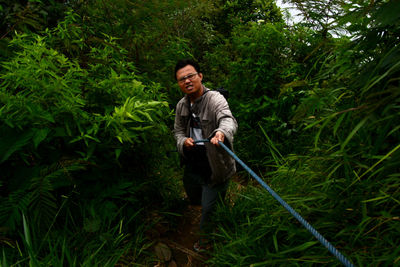 Full length of man pulling rope by trees at fore