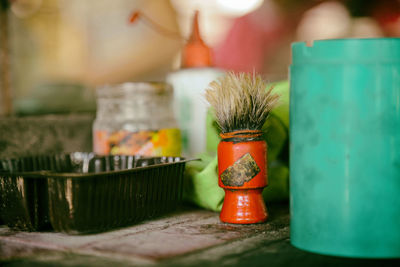 Close-up of shaving brush by containers on table