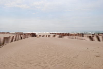 Wooden posts on beach against sky