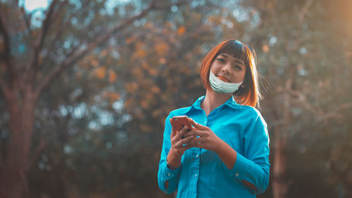 Portrait of teenage girl wearing sunglasses standing against trees