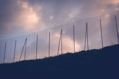 Low angle view of fence on field against sky