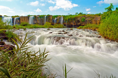 Scenic view of waterfall against sky