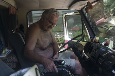 Shirtless man sitting in car