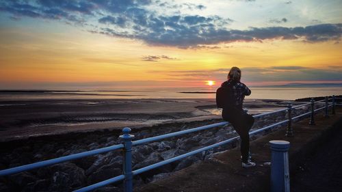 Man looking at sea against sky during sunset