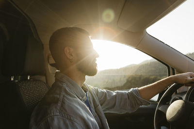 Young man driving van on sunny day