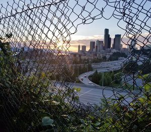 Scenic view of cityscape seen through chainlink fence