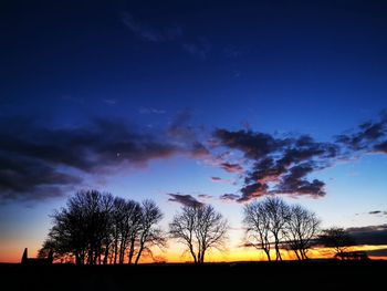 Silhouette trees on field against sky at sunset