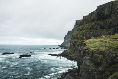 Scenic view of ocean by cliff against sky