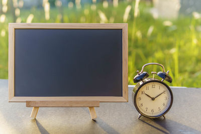 Close-up of alarm clock with blackboard on table