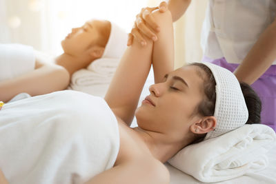 Cropped hands of massage therapist massaging young woman arm in spa