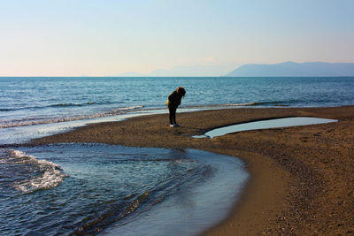 Indistinct figure of lonely woman at the sea on the beach in winter at sunset in tuscany dune