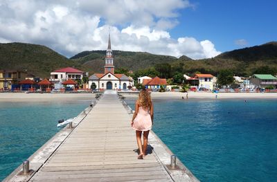 View of jetty in front of houses against sky