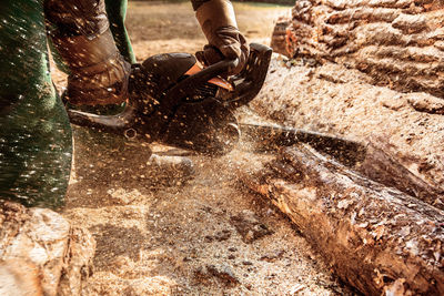 Midsection of person using chainsaw to cut wood