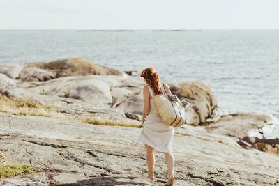 Rear view of young woman standing on beach