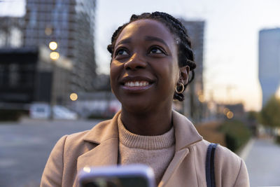 Smiling woman in city at dusk