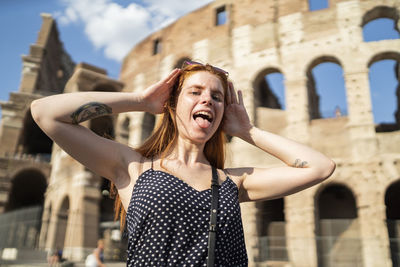 Happy woman grimacing near aged monument