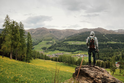 Rear view of man standing on mountain against sky