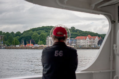 Rear view of man looking at river against sky