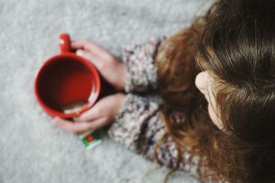 Directly above shot of girl holding tea on bed