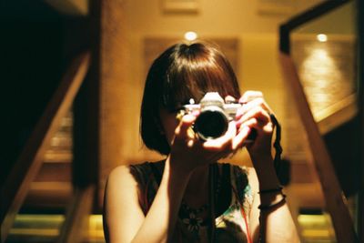 Close-up of woman photographing with camera at night