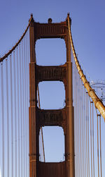 Low angle view of suspension bridge against blue sky