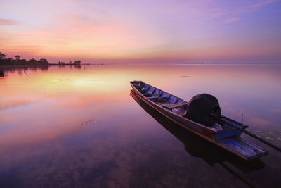 Boat moored in sea against sky during sunset